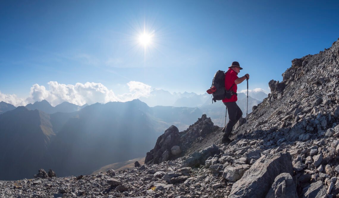 Border region Italy Switzerland, senior man hiking in mountain landscape at Piz Umbrail