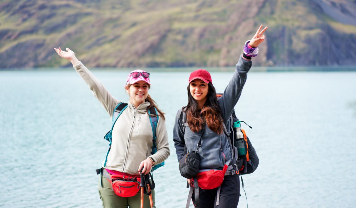 two latin women hikers backpackers posing happy with a lake in the background in Torres del Paine national park