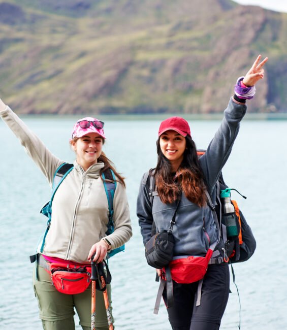 two latin women hikers backpackers posing happy with a lake in the background in Torres del Paine national park